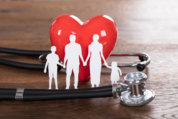 medical insurance concept with family cut out and stethoscope on wooden desk
