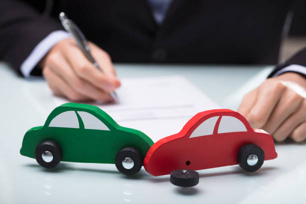 close up of red and green car in front of businessman writing on paper